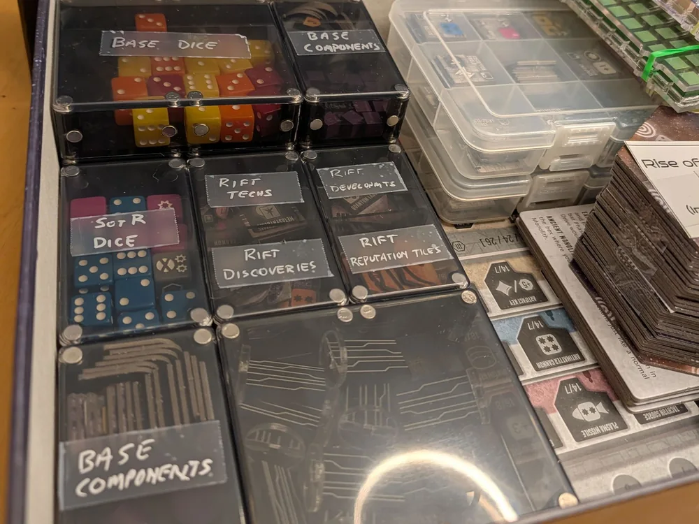 Hand-labelled Piece Keepers trays holding dice, tokens and cards inside a game box